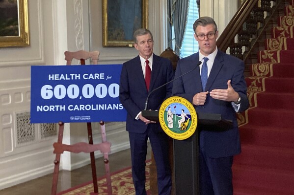 FILE - North Carolina Health and Human Services Secretary Kody Kinsley, right, speaks while Gov. Roy Cooper listens at an Executive Mansion news conference in Raleigh, N.C., Sept. 25, 2023. Enrollment in North Carolina's new Medicaid coverage for low-income adults has surpassed 400,000 in the expansion program's first four months, Cooper announced on Monday, April 1, 2024. (AP Photo/Gary D. Robertson, File)