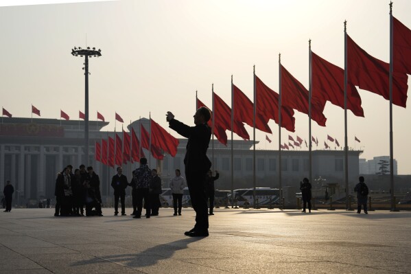 A man takes photos near red flags on Tiananmen Square before the closing session of the Chinese People's Political Consultative Conference (CPPCC) in Beijing, Sunday, March 10, 2024. The CPPCC is an advisory body to the National People's Congress which will close Monday. (AP Photo/Ng Han Guan)