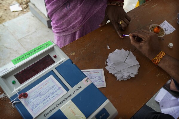 Εκλογικός υπάλληλος τοποθετεί ένα ανεξίτηλο σημάδι μελάνι στον δείκτη μιας γυναίκας ψηφοφόρου κατά την τέταρτη φάση των γενικών εκλογών, στα περίχωρα της Σαμαστιπούρ, στην πολιτεία Μπιχάρ της Ινδίας, Δευτέρα, 13 Μαΐου 2024. (AP Photo/Manish Swarup)