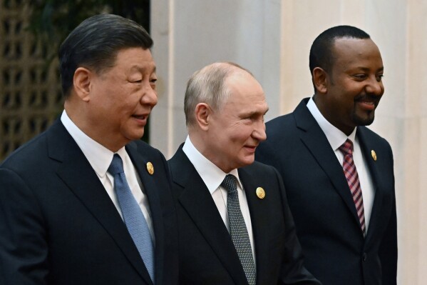 Chinese President Xi Jinping, left, Russian President Vladimir Putin, center, and Ethiopian Prime Minister Abiy Ahmed head to a group photo session at the Belt and Road Forum in Beijing Wednesday, on Wednesday, Oct. 18, 2023. (Grigory Sysoyev, Sputnik, Kremlin Pool Photo via AP)