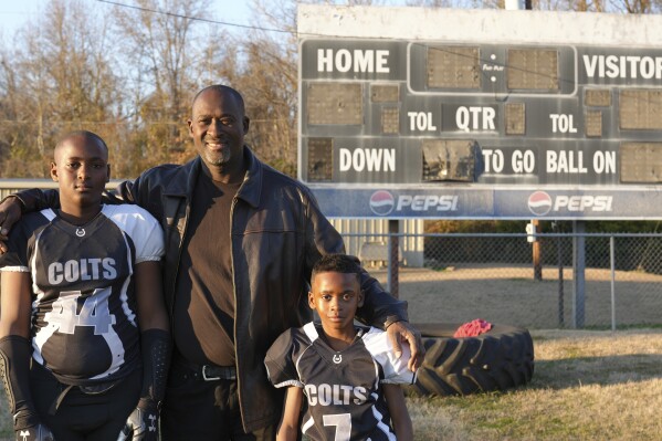 This photo provided by the University of Maryland shows Ronald Redmond standing with sons, 11-year-old R.J., left, and 7-year-old Mason on a football field in Lexington, Mississippi, Jan. 4, 2024. Lexington, Miss. is located in the second-poorest county in the nation’s poorest state. Yet a new analysis shows the town sends more players per capita to elite college football programs than any other town in Mississippi – at a rate that’s among the top in the nation. For many families, the game offers hope for college and a future. (University of Maryland/Jenna Bloom via AP)