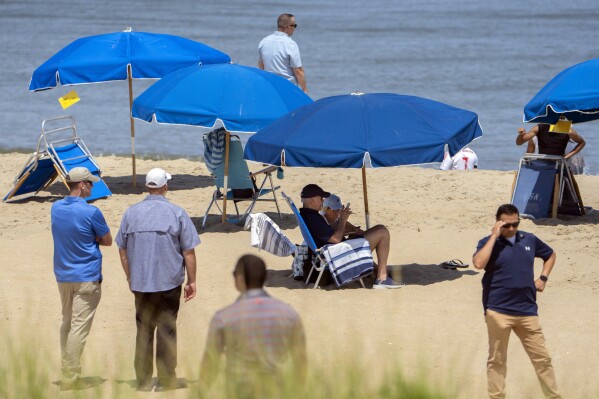 President Joe Biden and first lady Jill Biden sit underneath an umbrella surrounded by Secret Service agents on a beach in Rehoboth Beach, Del., Wednesday, Aug. 2, 2023. (AP Photo/Manuel Balce Ceneta)