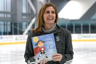 Seattle Kraken NHL hockey team pro scout Cammi Granato poses with her new book, "I Can Play Too," Wednesday, Feb. 2, 2022, in Seattle. For years, Hockey Hall of Famer Granato was asked to write a book about her experience in becoming one of the finest women's hockey players of all time. She finally has, but on her own terms and with a specific audience in mind—kids. And while her book is based around hockey and her personal experiences, Granato is hoping the message can resonate beyond the ice. (AP Photo/Elaine Thompson)