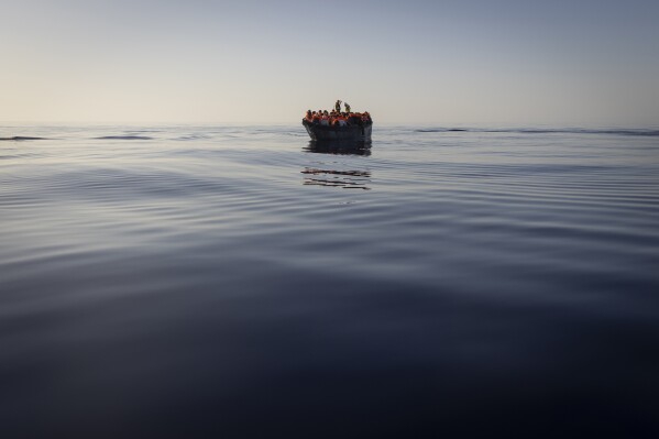 FILE - Migrants with life jackets provided by volunteers of the Ocean Viking, a migrant search and rescue ship run by NGOs SOS Mediterranee and the International Federation of Red Cross (IFCR), still sail in a wooden boat as they are being rescued, Aug. 27, 2022, in the Mediterranean sea. Greek authorities rescued 40 migrants from a sinking dinghy in the Aegean Sea on Wednesday, Aug. 2, 2023, and charged two of them with causing a shipwreck and endangering lives for allegedly scuttling the flimsy vessel as a coast guard boat approached. (AP Photo/Jeremias Gonzalez, File)