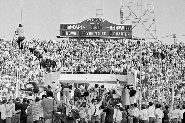 FILE - Joyous Oklahoma fans climb the goal posts to tear out the cross bar for souvenirs after the Oklahoma defeated Texas 18-9 in an NCAA college football game at the Cotton Bowl in Dallas, Oct. 8, 1966. The Big 12 is losing its marquee matchup when the Red River Rivalry is played Saturday for the final time under the league’s umbrella.(AP Photo/Ferd Kaufman, File)
