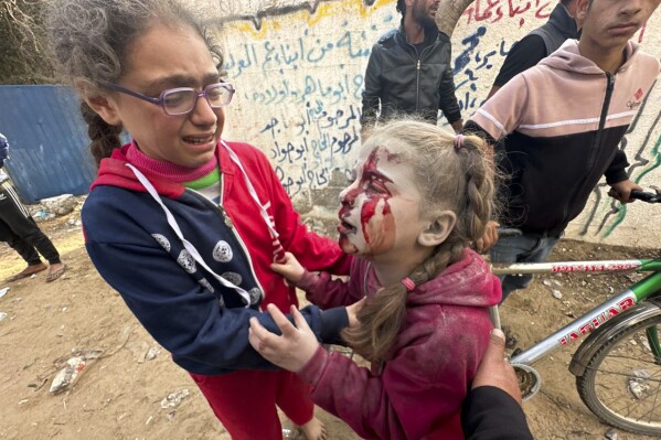 Ajudando uma menina palestina ferida após um ataque israelense a Al-Zawaida, no centro da Faixa de Gaza, quinta-feira, 28 de dezembro de 2023. (AP Photo/Mohammed Asad)