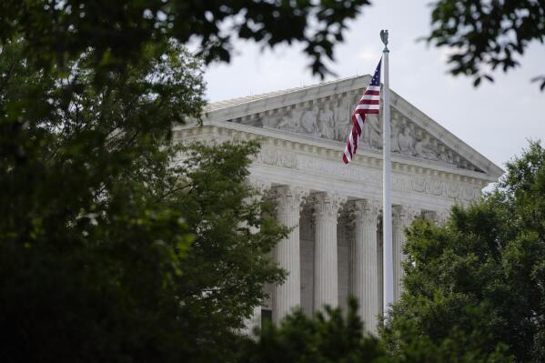 FILE - An American flag waves in front of the U.S. Supreme Court building in Washington, June 27, 2022. Supreme Court arguments are continuing long after a red light tells lawyers to stop. Arguments that usually lasted an hour have stretched beyond two this term so on many days it is well past lunchtime before the court breaks. (AP Photo/Patrick Semansky, File)