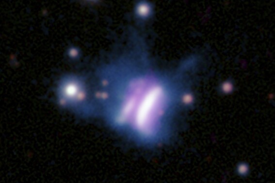 This composite radio and optical image provided by researchers in May 2024 shows IRAS 23077, center, a planet-forming disk, and several surrounding stars. The star at the center of IRAS 23077 is not visible because its light is blocked by its surrounding disk, which is viewed from the side. The diameter of this colossal disk is roughly 3,300 times the distance between Earth and the sun, with enough gas and dust to form super-sized planets in far-flung orbits, the U.S. and German researchers reported in May 2024. (Radio: SAO/ASIAA/SMA/K. Monsch et al; Optical: Pan-STARRS via AP)