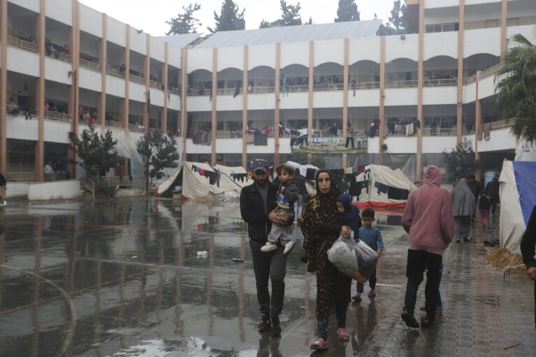 Displaced Palestinians walk inside a UN-run school during the fourth day of a temporary ceasefire between Hamas and Israel in Rafah, Gaza Strip, on Monday, November 27, 2023.  (AP Photo/Hatem Ali)