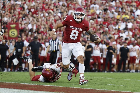 Oklahoma quarterback Dillon Gabriel (8) escapes a tackle by Iowa State defensive back Darien Porter (10) for a touchdown during the first half of an NCAA college football game Saturday, Sept. 30, 2023, in Norman, Okla. (AP Photo/Alonzo Adams)
