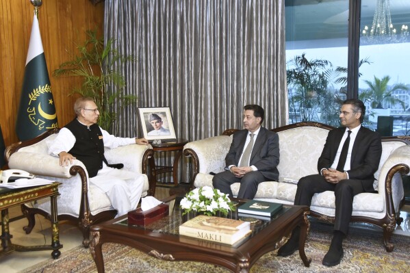 In this photo released by Press Information Department, Chief Election Commissioner Sikandar Sultan Raja, center, and Attorney General of Pakistan, Mansoor Usman Awan, right, meets with President Arif Alvi to finalised the date of general election, in Islamabad, Pakistan, Thursday, Nov. 2, 2023. Pakistan's election oversight body postponed the country's upcoming parliament elections for the second time, saying the vote — originally expected in November and then scheduled for the last week of January — will instead take place in February. (Press Information Department via AP)