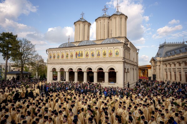 Romanian Orthodox priests and believers stand outside the Patriarchal Cathedral after an Orthodox Palm Sunday pilgrimage in Bucharest, Romania, Saturday, April 12, 2025. (AP Photo/Andreea Alexandru)