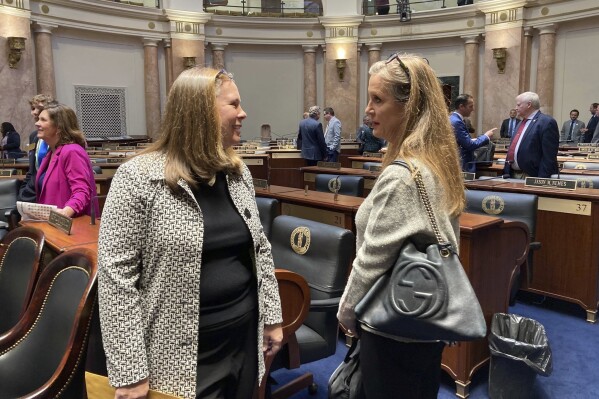 Kentucky Rep. Suzanne Miles, left, speaks with a colleague in the House chamber Friday, Jan. 26, 2024, in Frankfort, Ky. Miles introduced a school choice constitutional amendment that would go on Kentucky's November ballot if it wins legislative approval. (AP Photo/Bruce Schreiner)