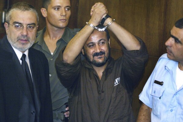 FILE - Marwan Barghouti, center, raises his handcuffed hands in the air on the opening day of his trial at Tel Aviv's District Court on Aug. 14, 2002. Hamas officials say that any cease-fire deal with Israel should include the release of prisoner Marwan Barghouti — a leader of the militant group's main political rival. The demand by Hamas marks the central role Barghouti plays in Palestinian politics — even after more than two decades behind bars and sentenced by Israel to multiple life terms in prison. (AP Photo/Brennan Linsley, File)