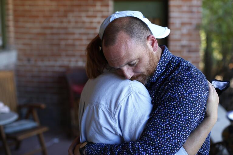 Matthew and Miranda Whitworth embrace at the home of the attorney representing their adoptive daughter in a lawsuit against The Church of Jesus Christ of Latter-day Saints, in Tucson, Ariz., Saturday, Oct. 30, 2021. The Whitworths said they hope the lawsuit forces the church to change church policy so that any instance of child sexual abuse is immediately reported to civil authorities. “We just don’t understand why they’re paying all these lawyers to fight this,” Matthew said. “Just change the policy.” (AP Photo/Dario Lopez-Mills)