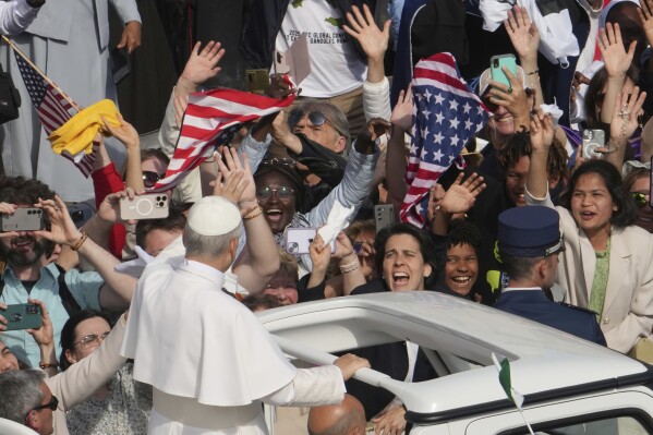 Faithful wave flags of the United States of America as Pope Leo XIV on his popemobile tours St. Peter's Square at the Vatican prior to the inaugural Mass of his pontificate, Sunday, May 18, 2025. (AP Photo/Domenico Stinellis)
