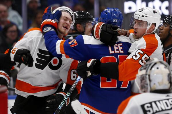 New York Islanders left wing Anders Lee (27) hits Philadelphia Flyers defenseman Travis Sanheim (6) while being restrained by Flyers defenseman Rasmus Ristolainen (55) during the second period of an NHL hockey game Saturday, Nov. 26, 2022, in Elmont, N.Y. (AP Photo/John Munson)