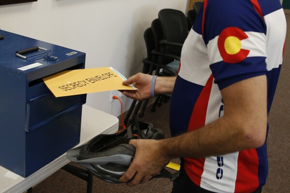 FILE - A voter places his ballot into a collection box after filling it in at a polling center, on state primary election day, in Boulder, Colo., June 28, 2016. Colorado voters will decide two statewide ballot measures Tuesday that would impact their pocketbooks as well as state coffers. (AP Photo/Brennan Linsley, File)