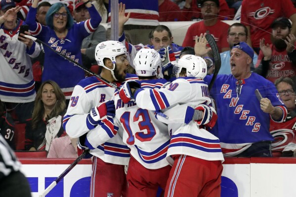New York Rangers left wing Alexis Lafrenière (13) celebrates his goal against the Carolina Hurricanes with defenseman K'Andre Miller (79) and left wing Artemi Panarin (10) during the third period in Game 3 of an NHL hockey Stanley Cup second-round playoff series Thursday, May 9, 2024, in Raleigh, N.C. (AP Photo/Chris Seward)
