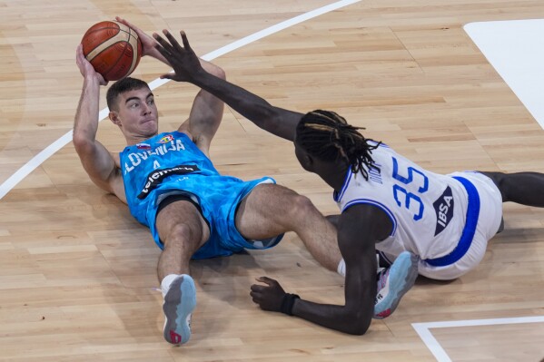 Slovenia guard Ziga Samar (4) makes a pass from the floor over Italy center Mouhamet Diouf (35) during a classification game at the Basketball World Cup in Manila, Philippines Saturday, Sept. 9, 2023. (AP Photo/Michael Conroy)