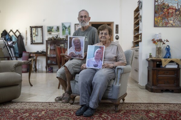 Chanan Choen, along with his wife, Edna Choen, hold up portraits of his sister, 77-year-old Margalit Moses, and her husband, 79-year-old Gadi Moses in their family home in Lakhish in central Israel, Monday, Oct. 30, 2023. The elderly Moses couple, both Israeli citizens, were abducted by Hamas fighters from their home in the kibbutz of Nir Oz during the group's unprecedented attack on Oct. 7 that resulted in the killing over 1,400 people and abduction of over 220. (AP Photo/Ohad Zwigenberg)