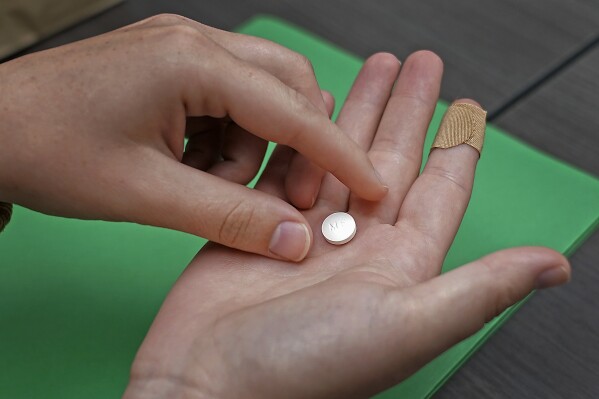 FILE - A patient prepares to take the first of two combination pills, mifepristone, for a medication abortion during a visit to a clinic in Kansas City, Kan., on, Oct. 12, 2022. On Wednesday, Feb. 7, 2024, the medical journal Sage Perspectives retracted studies claiming to show the harms of mifepristone, citing conflicts of interest by the authors and flaws in the research. (AP Photo/Charlie Riedel, File)