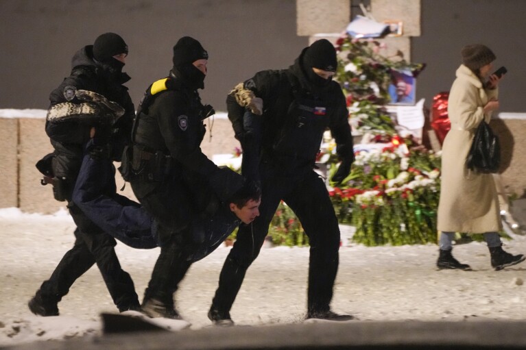 FILE - Police detain a man laying flowers in tribute to the late Alexei Navalny at the Memorial to Victims of Political Repression in St. Petersburg, Russia, on Friday, Feb. 16, 2024. Navalny, the fiercest political foe of Russian President Vladimir Putin who crusaded against official corruption and staged massive anti-Kremlin protests, died while in prison. He was 47. (AP Photo, File)