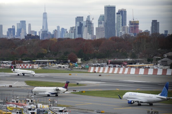 FILE - The New York City skyline is seen behind planes waiting to take off at LaGuardia Airport in New York, Nov. 22, 2023. Most Americans believe that air travel is generally safe in the U.S., despite some doubts about whether aircraft are being properly maintained and remain free from structural problems.(AP Photo/Seth Wenig, File)