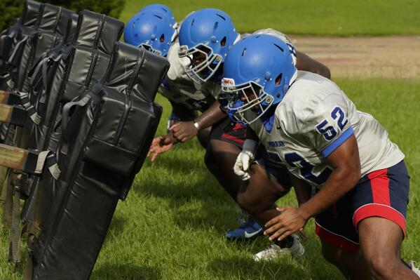 Murrah High School football offensive linemen square up against the blocking sled at practice, Wednesday, Aug. 31, 2022, in Jackson, Miss. The city's low water pressure concerns football coach Marcus Gibson, as it limits his options for washing practice uniforms, towels and other gear his players wear. The recent flood worsened Jackson's longstanding water system problems. (AP Photo/Rogelio V. Solis)