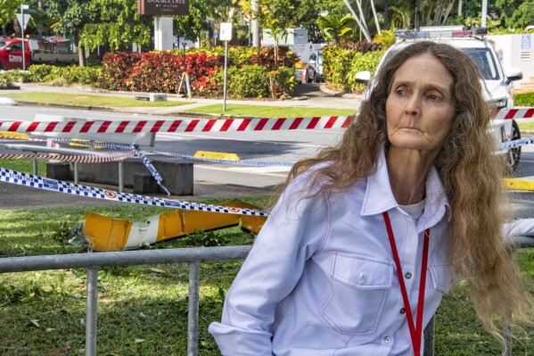 Witness Veronica Knight walks past a piece of helicopter wreckage in Cairns, Australia, following the crash of the aircraft, Monday, Aug. 12, 2024. (Brian Cassey/AAP Image via AP)