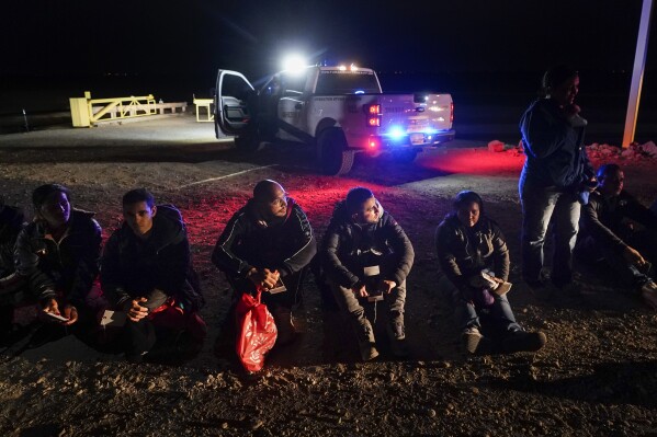 FILE - Migrants wait to be processed after crossing the border, Jan. 6, 2023, near Yuma, Ariz. A federal judge on Tuesday, July 25, blocked a rule that allows immigration authorities to deny asylum to migrants who arrive at the U.S.-Mexico border without first applying online or seeking protection in a country they passed through. But the judge delayed his ruling from taking effect immediately to give the administration time to appeal. (AP Photo/Gregory Bull, File)