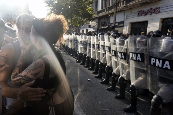 Riot police stand in a phalanx formation as people protest outside Congress where lawmakers are debating a bill promoted by Argentine President Javier Milei in Buenos Aires, Argentina, Wednesday, Jan. 31, 2024. The bill includes a broad range of economic, administrative, criminal and environmental reforms. (AP Photo/Rodrigo Abd)