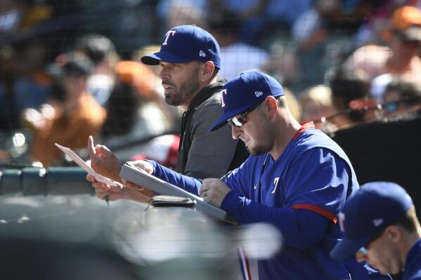 Texas Rangers manager Chris Woodward, left, looks on from the dugout in the fifth inning of a baseball game against the Baltimore Orioles, Sunday, Sept. 26, 2021, in Baltimore. (AP Photo/Gail Burton)