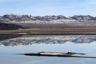FILE - Mountains are reflected in an evaporation pond at the Silver Peak lithium mine in Esmeralda County, Nev. on Jan. 30, 2017. An Indiana couple missing for about a week has been found near the remote mountain area of southern Nevada, but the husband was dead and the wife was taken to a hospital, a sheriff's official said. Ronnie Barker, 72, and Beverly Barker, 69, were found with their car late Tuesday, April 5, 2022, afternoon in the Silver Peak area of Esmeralda County, Mineral County Undersheriff Bill Ferguson said during a telephone interview. (Steve Marcus/Las Vegas Sun via AP, File)