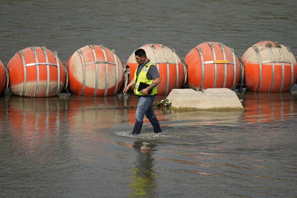 A worker inspects buoys being used as a barrier along the Rio Grande, Monday, Aug. 21, 2023, in Eagle Pass, Texas. (AP Photo/Eric Gay)