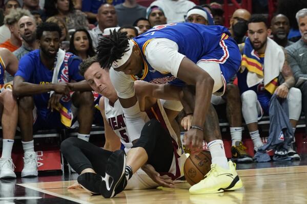 Golden State Warriors center Kevon Looney (5) and Miami Heat guard Duncan Robinson (55) go after a loose ball during the first half of an NBA basketball game, Wednesday, March 23, 2022, in Miami. (AP Photo/Marta Lavandier)