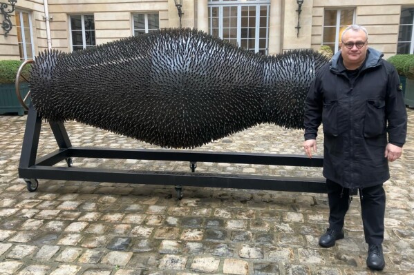 Ukraine's Mikhail Reva poses next to one of his art pieces, Thursday, Feb. 22, 2024 in Paris. From within the debris of Russia's war, Ukraine's most famous sculptor was compelled to take a dark artistic pivot and express his homeland's suffering the day his own country house was ravaged by a Russian strike. (AP Photo/Thomas Adamson