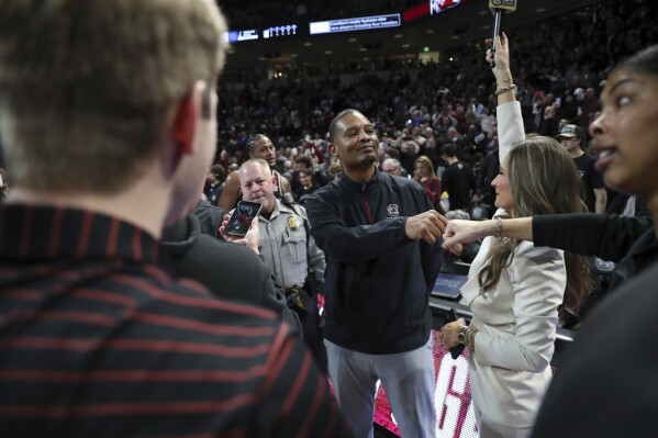 South Carolina head coach Lamont Paris is congratulated by a fan while he waits to be interviewed after upsetting Kentucky during an NCAA college basketball game Tuesday, Jan. 23, 2024, in Columbia, S.C. South Carolina won 79-62. (AP Photo/Artie Walker Jr.)