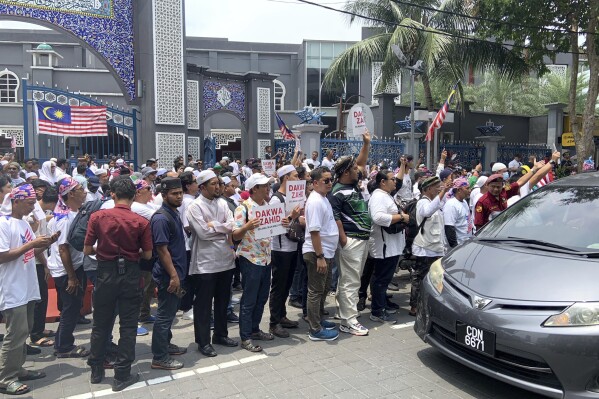 Demonstrators stage a protest outside a mosque with signs reading 