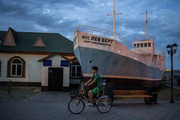 A boy rides a bicycle in what used to be the main port of Aralsk, Kazakhstan, before the Aral Sea dried up, Tuesday, July 4, 2023. (AP Photo/Ebrahim Noroozi)