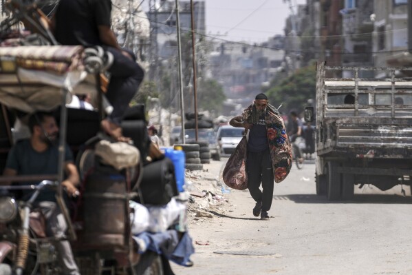 A Palestinian carries his belongings as he evacuates Maghazi refugee camp in the central Gaza Strip, as part of a mass evacuation ordered by the Israeli military ahead of an operation, Saturday, Aug. 17, 2024. (AP Photo/Abdel Kareem Hana)