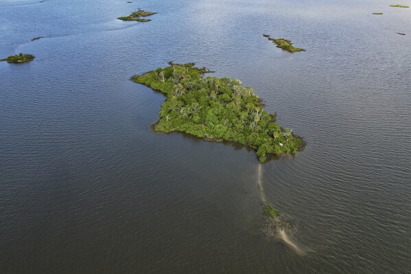 Sweetheart Island, center, off the coast of Yankeetown, Fla., is seen on Aug. 5, 2023. While Patrick Parker Walsh's private island ranks among the most unusual purchases by pandemic fraudsters, his crime was not unique. He is one of thousands of thieves who perpetrated the greatest grift in U.S. history. They potentially plundered more than $280 billion in federal COVID-19 aid; another $123 billion was wasted or misspent. (AP Photo/Julio Aguilar)
