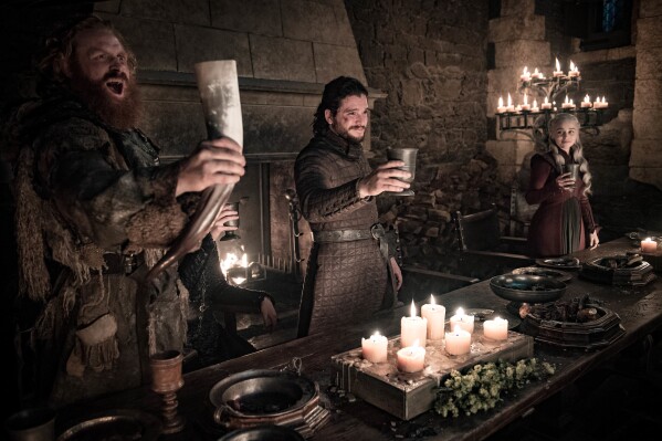 This image released by HBO shows Kristofer Hivju, from left, Kit Harington and Emilia Clarke in a scene from "Game of Thrones." The 75th Emmy Awards will include cast reunions and recreations of classic moments from a dozen iconic shows throughout television history, including "Game of Thrones." (Helen Sloan/HBO via AP)
