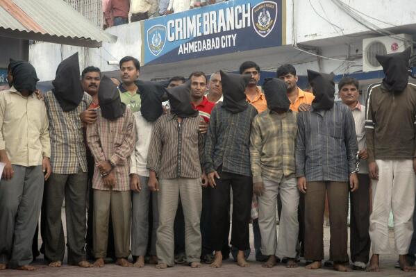 FILE- Nine men, wearing black hoods to conceal their identity, arrested by the Ahmedabad crime branch for allegedly conducting a series of bombings, are shown to the media in Ahmadabad, India, Saturday, Aug. 16, 2008. A court on Friday sentenced 38 convicts to death by hanging after finding them guilty of 2008 serial blasts that rocked a western Indian city that killed more than 50 people and left 200 injured. This is the first time that so many accused have been sentenced to death in a single case in India. The punishment will now be required to be confirmed by a higher court. (AP Photo/Ajit Solanki, File)