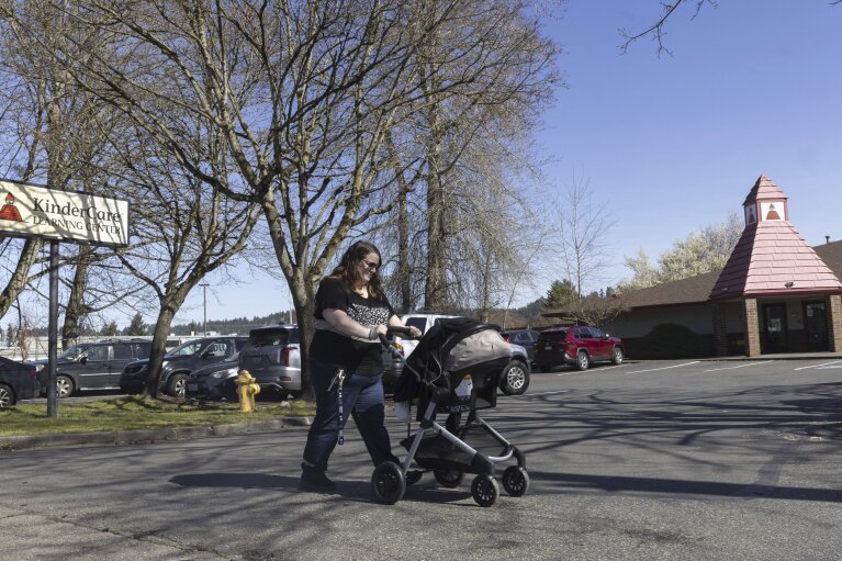 Nicole Slemp, a new mother of seven-month-old William, pushes her son in his stroller past KinderCare, which is near the family's home Thursday, March 14, 2024 in Auburn, Wash. Slemp recently quit her job because she and her husband couldn't find child care they could afford. Expensive, scarce child care is putting Puget Sound parents out of work. (Ellen M. Banner/The Seattle Times via AP)