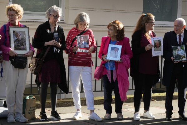Bereaved families hold pictures of their loved ones as they stand outside the opening hearing of Module 2 of the UK Covid 19 Inquiry, in London, Tuesday, Oct. 3, 2023. Bereaved families are coming together to protest the fact that in the module investigating core government decision making during the pandemic, only 1 bereaved family witness has been called to give evidence, out of the over 230,115 families bereaved by Covid 19. (AP Photo/Kirsty Wigglesworth)
