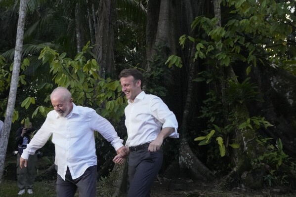 Brazil's President Luiz Inacio Lula da Silva, left, and French President Emmanuel Macron arrive on Combu Island, near Belem, Para state, Brazil, Tuesday, March 26, 2024. (AP Photo/Eraldo Peres).