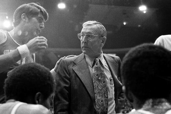 CORRECTS THE LOCATION TO CHICAGO AND NOT LOS ANGELES AS ORIGINALLY SENT - FILE - UCLA coach John Wooden listens to Greg Lee, left, during a timeout in the team's NCAA college basketball game against Iowa in January 1974 in Chicago. Lee, who helped UCLA to consecutive national championships in 1972 and '73 as a starting guard under Wooden, has died. He was 70. Lee died at a San Diego hospital Wednesday, Sept. 21, 2022, from an infection related to an immune disorder, the university said Thursday after being informed by his wife, Lisa. (AP Photo, File)