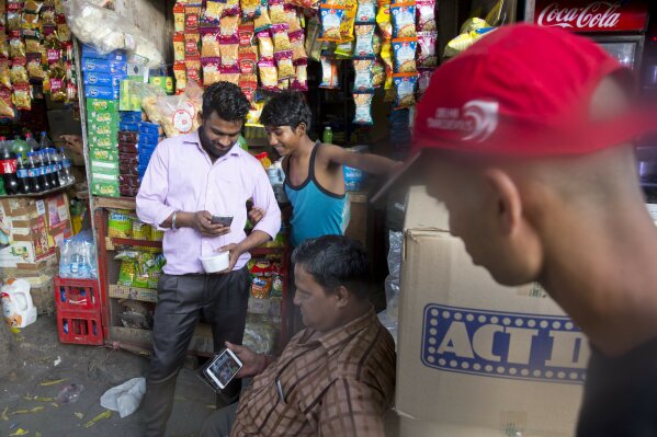 
              In this Monday, April 8, 2019, photo, Ram Shankar Rai, center, watches election campaign advertisements on his mobile phone outside his shop in New Delhi, India. From manipulated pictures being picked up by mainstream news media, to misrepresented quotes sparking communal division, false news and hateful propaganda on digital platforms are at peak levels in the run-up to the Indian general elections. (AP Photo/Manish Swarup)
            