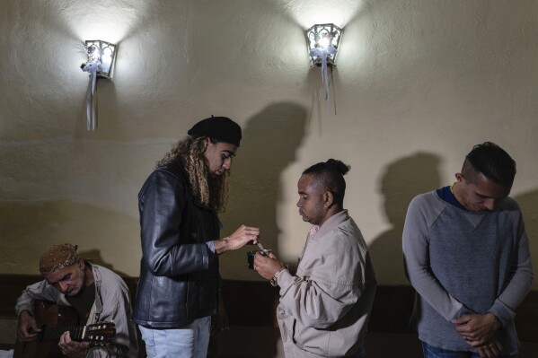 Mario Amilcar, center left, prepares to give Holy Communion to a fellow congregant during a service at the Metropolitan Community Church, an LGBTQ+ inclusive house of worship, in Matanzas, Cuba, Friday, Feb. 2, 2024. In recent years, the communist-run island barred anti-gay discrimination, and a 2022 government-backed “family law” allowed same-sex couples the right to marry and adopt. (AP Photo/Ramon Espinosa)